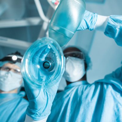 bottom view of african american anesthetist holding oxygen mask above patient